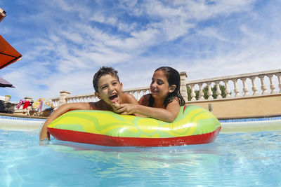 Two funny kids in the pool on an air mattress