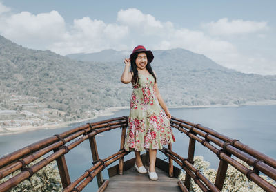 Woman standing on railing against mountains