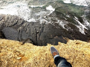 Low section of person on mountain by sea