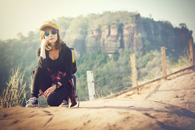 Young woman sitting on rock against mountain