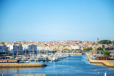 View of harbor in city against clear blue sky