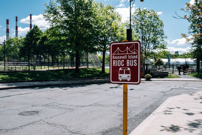 Information sign on street in city against sky