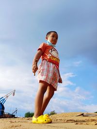 Portrait of young woman standing on beach against sky