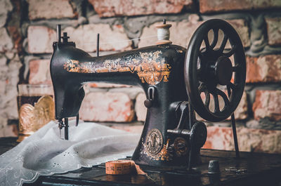 Close-up of sewing machine against brick wall