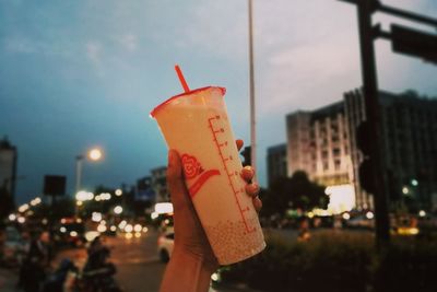 Close-up of hand holding illuminated city against sky