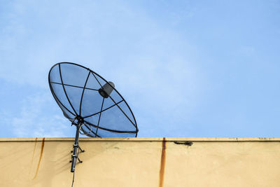 Black satellite disk on deck of building in sunny day