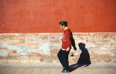 Full length of person sitting on wall