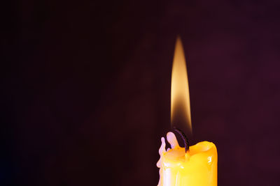 Close-up of lit candle in darkroom
