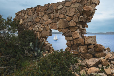 A sailing in perfect view through a stone wall -  la maddalena 