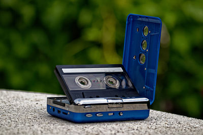 Close-up of audio cassette with radio on retaining wall
