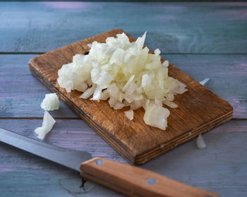 Chopped onions on a cutting board and a kitchen node lie on a wooden table. cooking blank