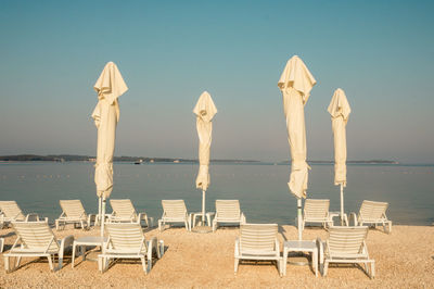 Chairs on beach against clear sky