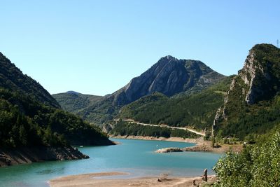 Scenic view of lake and mountains against clear blue sky