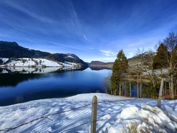 Scenic view of lake by snowcapped mountains against sky