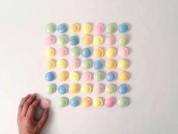 Directly above view of person arranging candies against white background