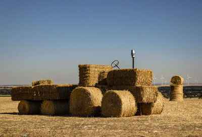 Hay bales on field against clear sky