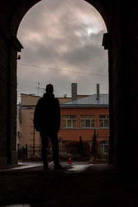 Rear view of silhouette man standing on street against sky