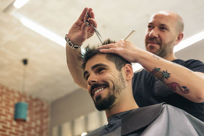 Low angle view of smiling barber and customer in salon