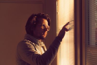 Mid adult man looking through window at home