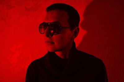 Man with sunglasses against red wall