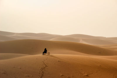 Man on sand dune in desert against sky