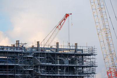 Cranes at construction site against sky