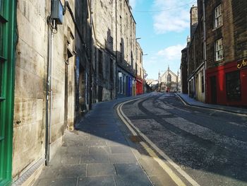 Empty road amidst buildings in city