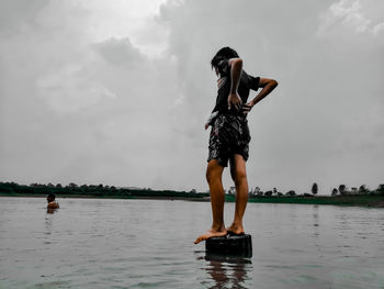 Rear view of woman standing in water against sky