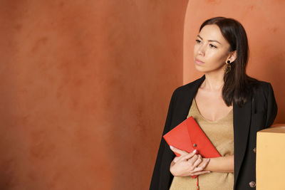 Close-up view of woman wearing black jacket and holding book with an empty red
