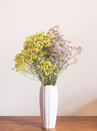 Close-up of flower vase on table against wall