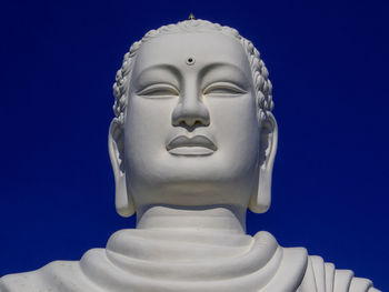 Close-up of buddha statue against blue sky