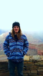 Portrait of man standing by retaining wall at grand canyon