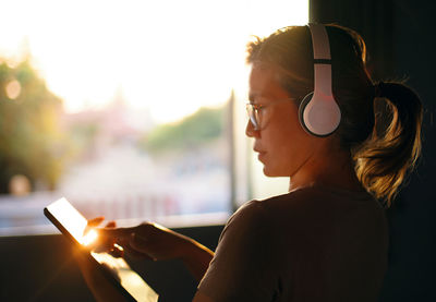A woman uses a tablet during listening to music with the headphone