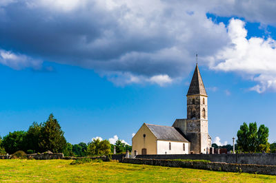 Church on field by building against sky