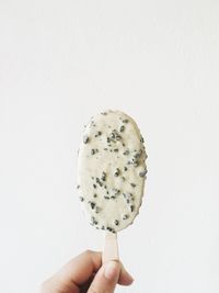 Close-up of hand holding ice cream against white background