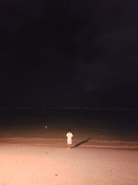 Rear view of woman standing on beach against sky