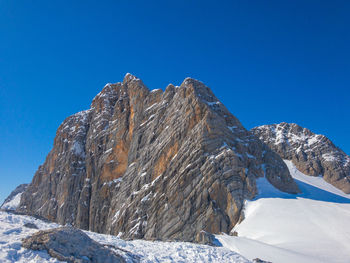 Low angle view of snowcapped dachstein against clear blue sky