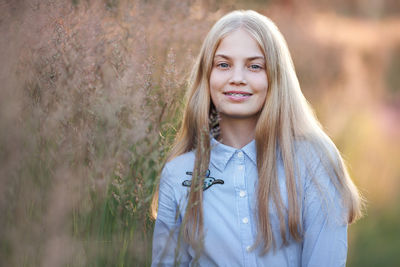 Beautiful teen girl with braces on teeth smiling. portrait of blonde model with long hair in nature