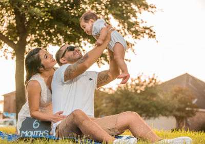 Father and mother playing with cute son while sitting on grassy field