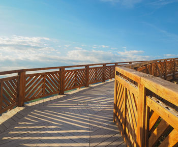 Wooden railing on beach against sky