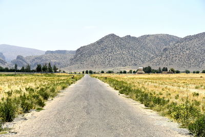 Road leading towards mountains against sky