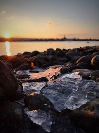 Rocks on beach against sky during sunset