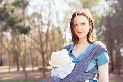 Portrait of woman with baby against trees