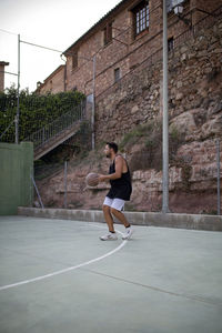 Full length of man playing basketball in court