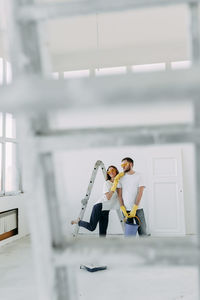 Happy smiling married couple engaged in renovation repair in the room of the house preparing to move