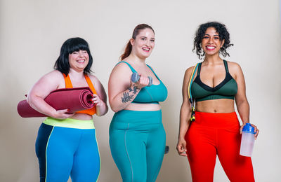 Portrait of happy friends standing against colored background