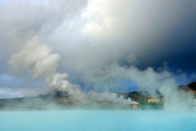 Smoke emitting from sea against sky