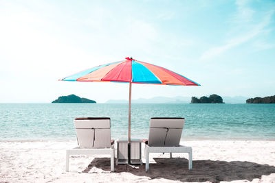 Bench and umbrella on the beach facing the sea