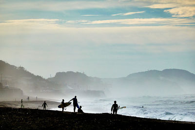 Silhouette people on beach against sky