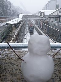 Snow covered railroad tracks against sky in city